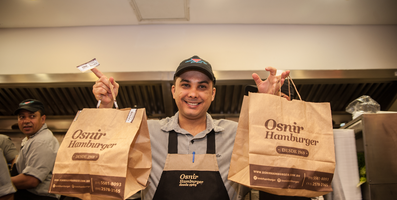 Entregador da Osnir Hamburger com sacolas de pedidos