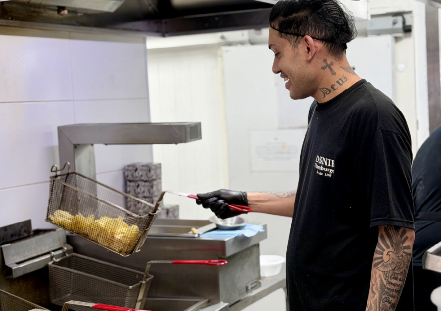 Garçom da Osnir servindo hambúrgueres e batatas
